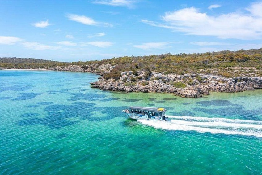 Ein Boot auf klarem, türkisblauem Wasser in der Nähe einer felsigen Küste. 1