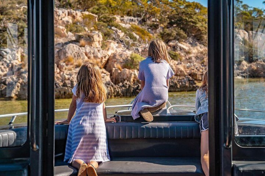 Trois personnes à bord d’un bateau, une côte rocheuse et une eau calme. 2