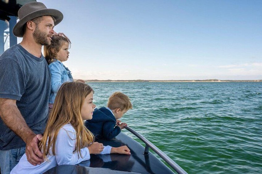 Eine Familie auf einem Boot bei ruhiger See und blauem Himmel. 3