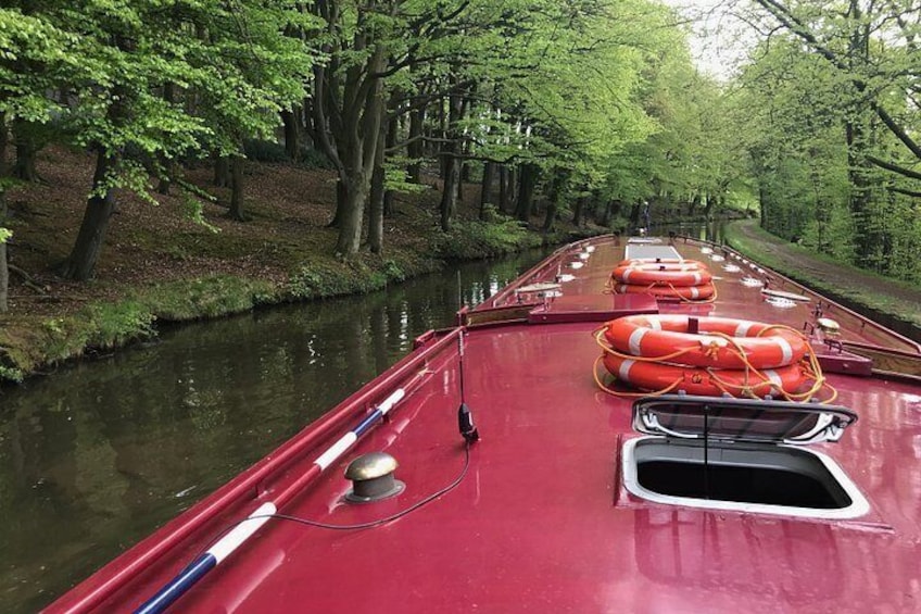 Un bote rojo con boyas salvavidas en una vía fluvial estrecha rodeada de árboles. 3