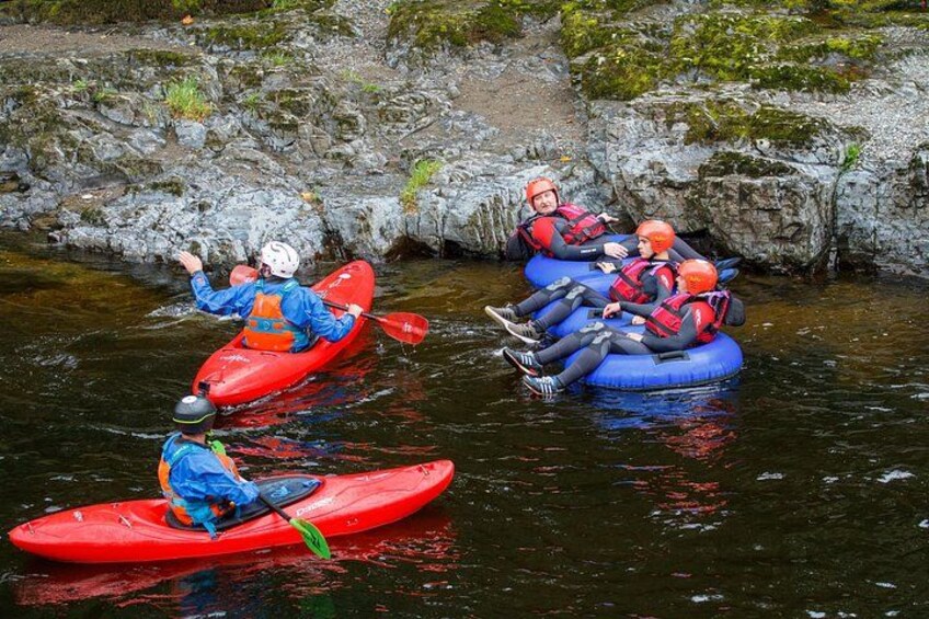 Three people kayaking on a river, surrounded by rocks and greenery. 5