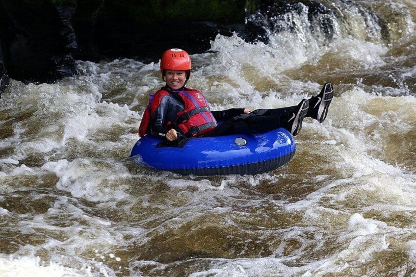 A person in a blue inflatable raft navigating a river with rapids. 4