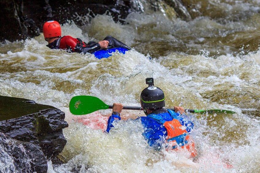 Two kayakers navigating through a turbulent river. 2