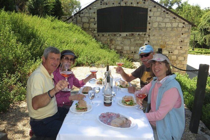 Un grupo de personas cenando al aire libre en una mesa con comida y bebidas. 1