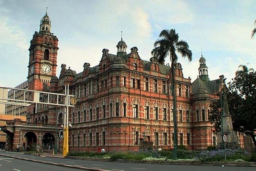 A large, ornate building with a clock tower, surrounded by palm trees and a street. 2