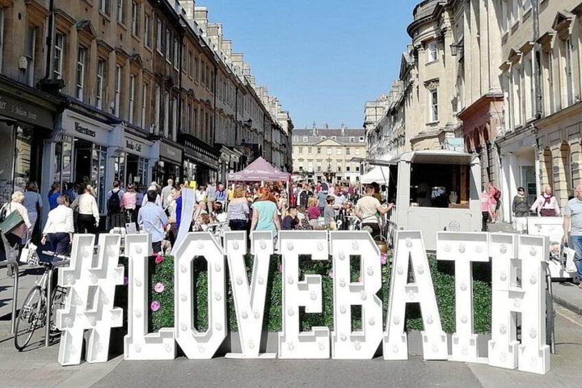 Una calle con un letrero iluminado grande que dice 'LOVEBATH' y una multitud de personas. 2