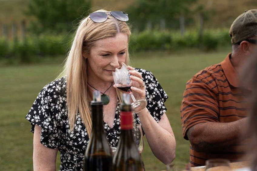 A person holding a wine glass, with bottles of wine on the table. 1