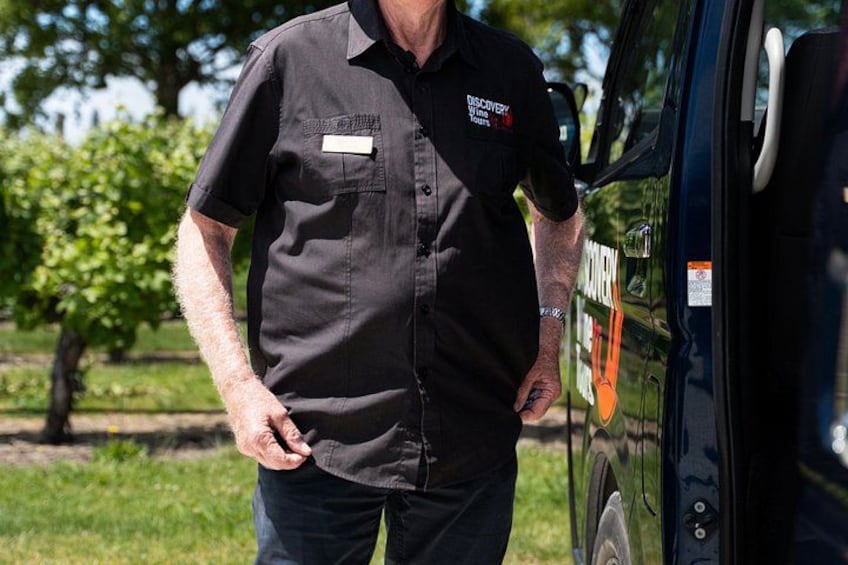 A man in a black shirt with a name tag standing next to a vehicle. 4