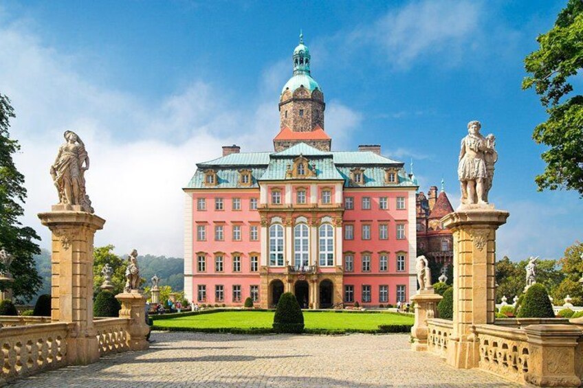 Ein großes, mehrfarbiges Gebäude mit einer Kuppel und Statuen davor. 5