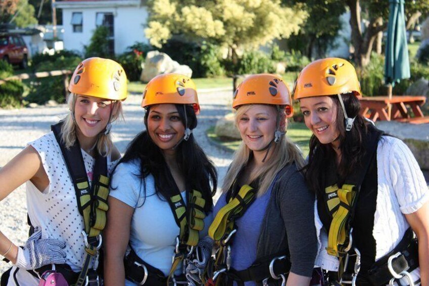 Four people wearing helmets and harnesses, likely engaged in a zip-lining activity. 4
