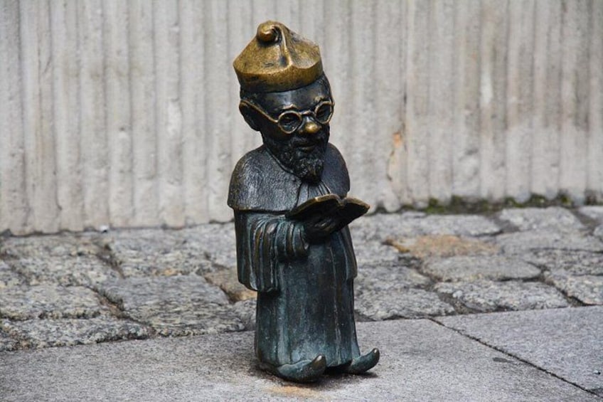 A statue of a person wearing a hat and holding a book. 3