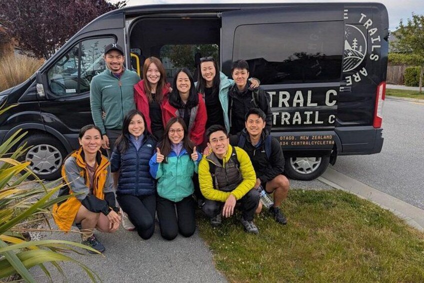 A group of people posing in front of a black van with 'TRAIL CYCLE' written on it. 3