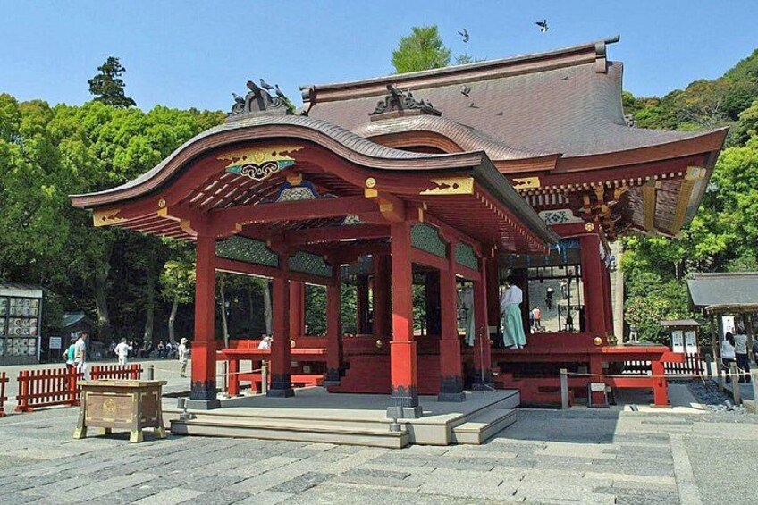 En traditionel japansk pavillon med et buet tag og røde søjler, omgivet af stenhinder og et hegn. 4