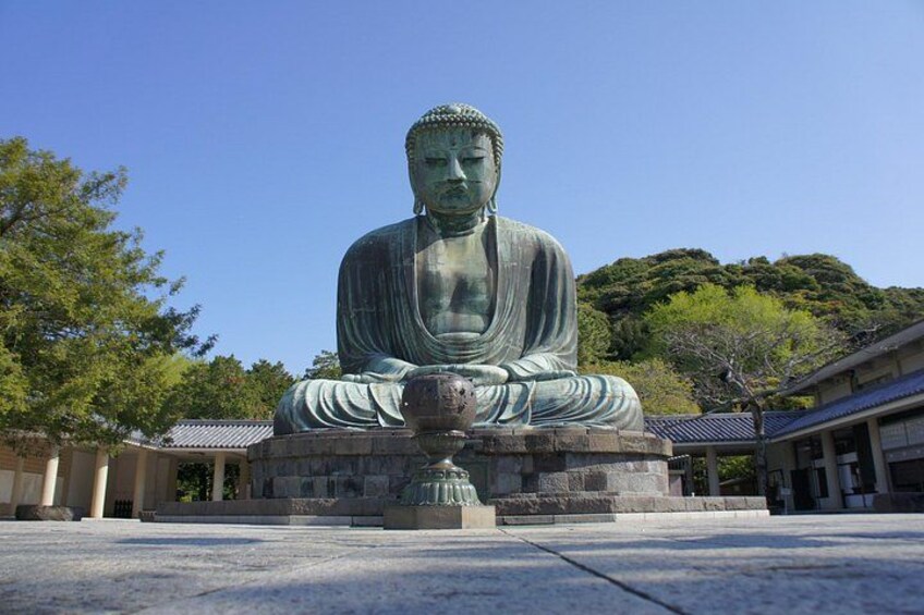 En stor siddende Buddha-statue i en gårdhave med traditionelle bygninger i baggrunden. 3