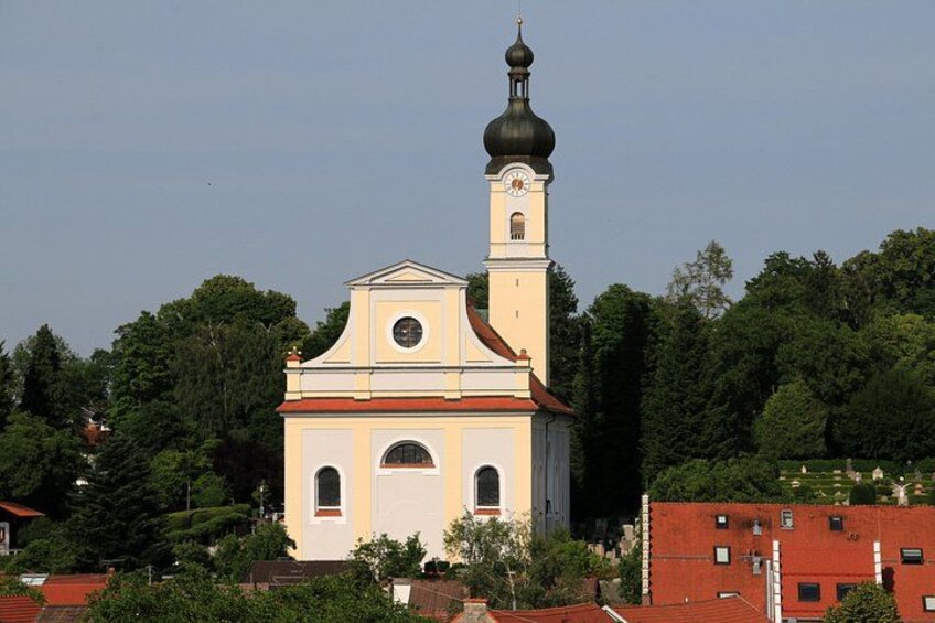 Una iglesia con campanario y cúpula, rodeada de árboles y edificios. 2
