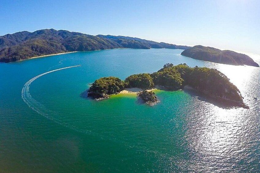 An aerial view of a large body of water with a curved shoreline, surrounded by forested hills. 2