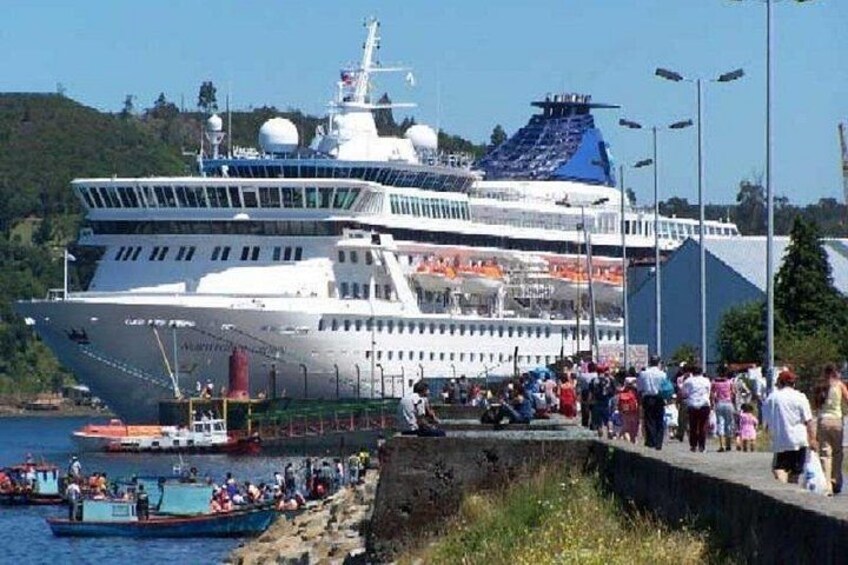 Un gran crucero atracado en un puerto, con gente en el muelle. 2