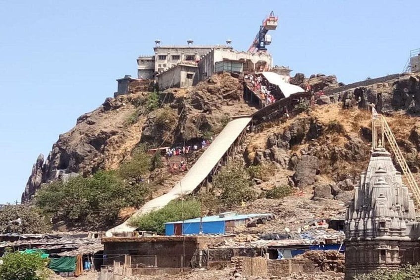 A temple on a rocky hill with a steep staircase and a large building at the top. 4