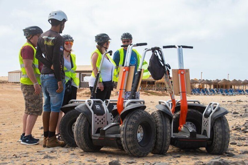 Un groupe de personnes se tient sur une plage de sable, à proximité de quads. 5