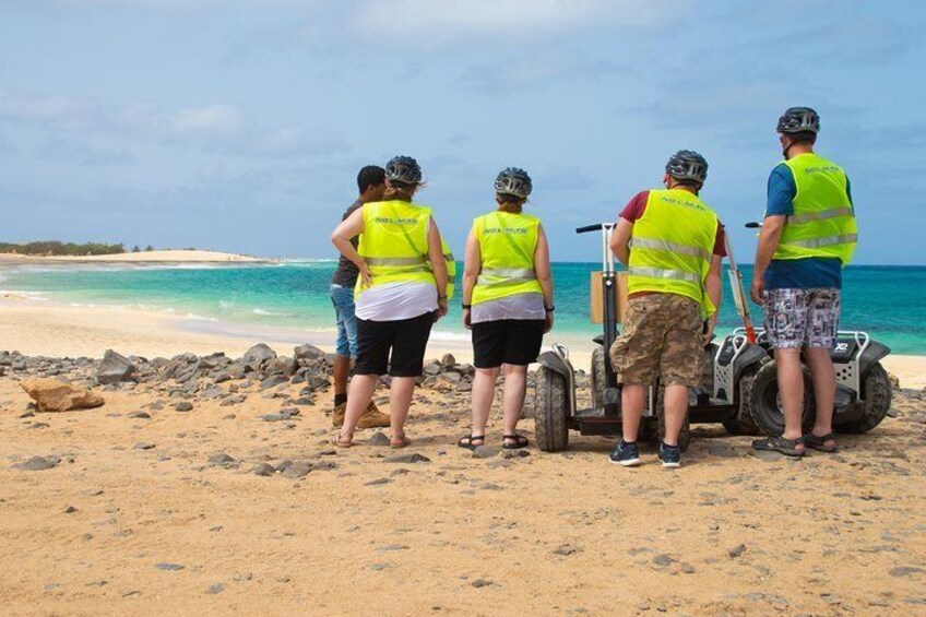Un groupe de personnes portant des gilets de sécurité se trouve sur une plage, à proximité d’un véhicule tout-terrain. 4