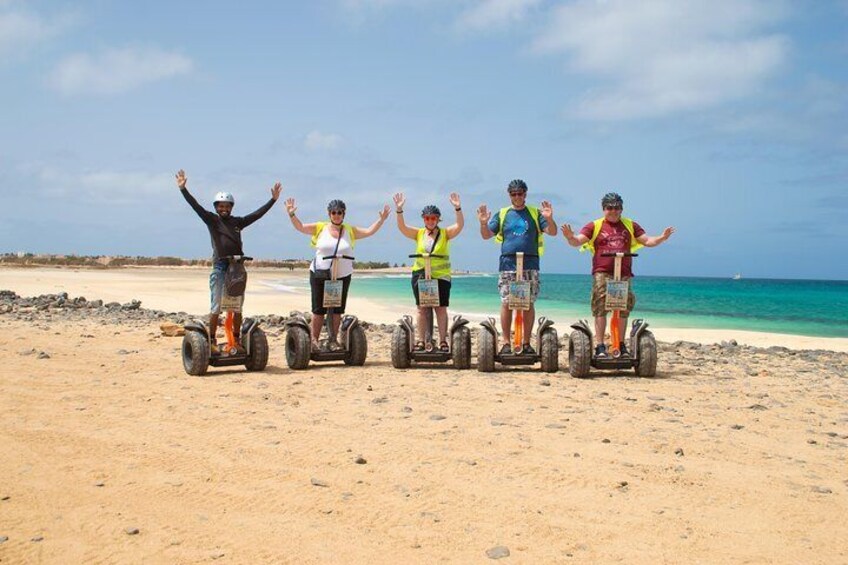 Quatre personnes sur des gyropodes sur une plage de sable, avec l’océan en arrière-plan. 2