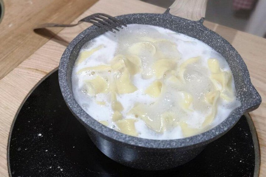 A bowl of soup with dumplings on a black plate. 2