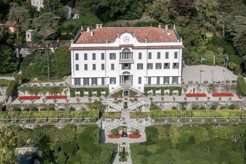 A large white building with a red-tiled roof, surrounded by well-maintained gardens and a central staircase. 5