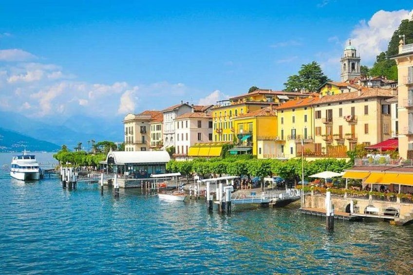 A waterfront with colorful buildings, a docked boat, and a clear blue sky. 2