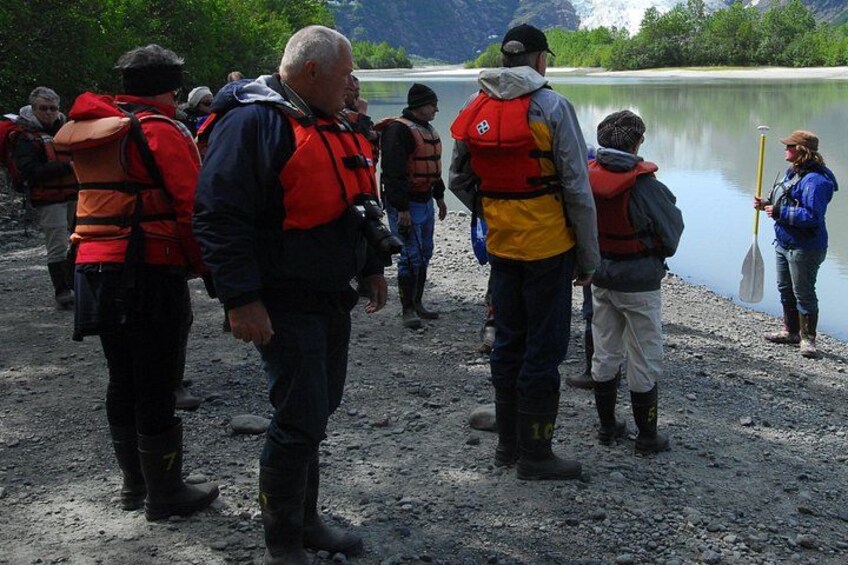 People wearing life jackets near a calm lake with mountains in the background. 2