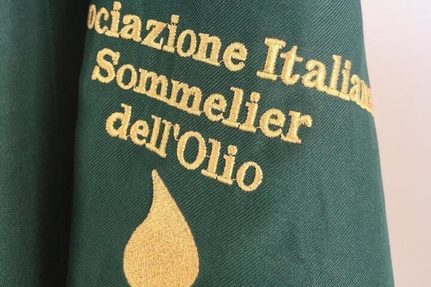 A green fabric with embroidered text and a gold droplet design. 1