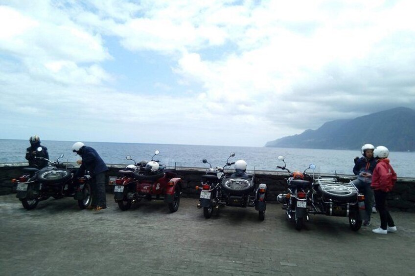A group of motorcycles parked by a waterfront with a cloudy sky. 4