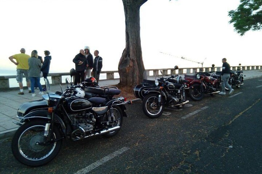 A row of motorcycles parked along a waterfront promenade. 2