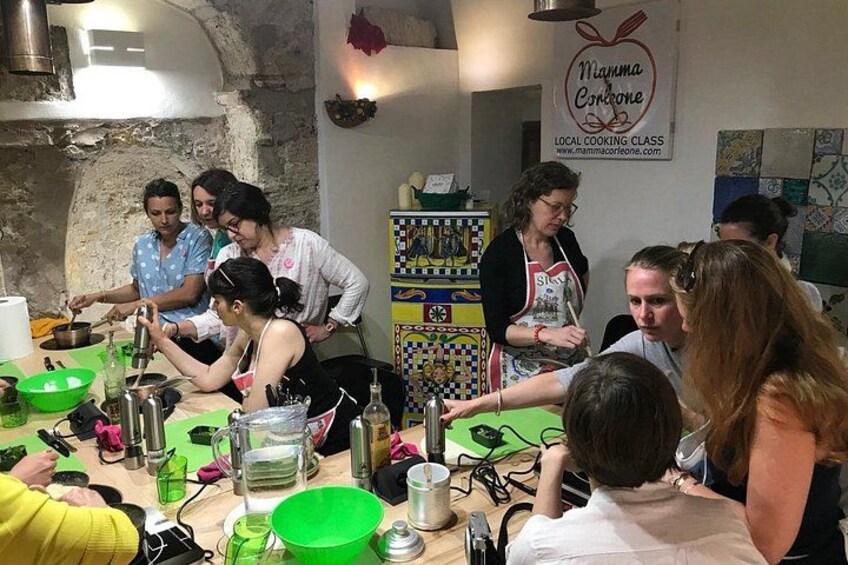Un groupe de personnes participe à un cours de cuisine, avec des ustensiles et des ingrédients disposés sur la table. 1