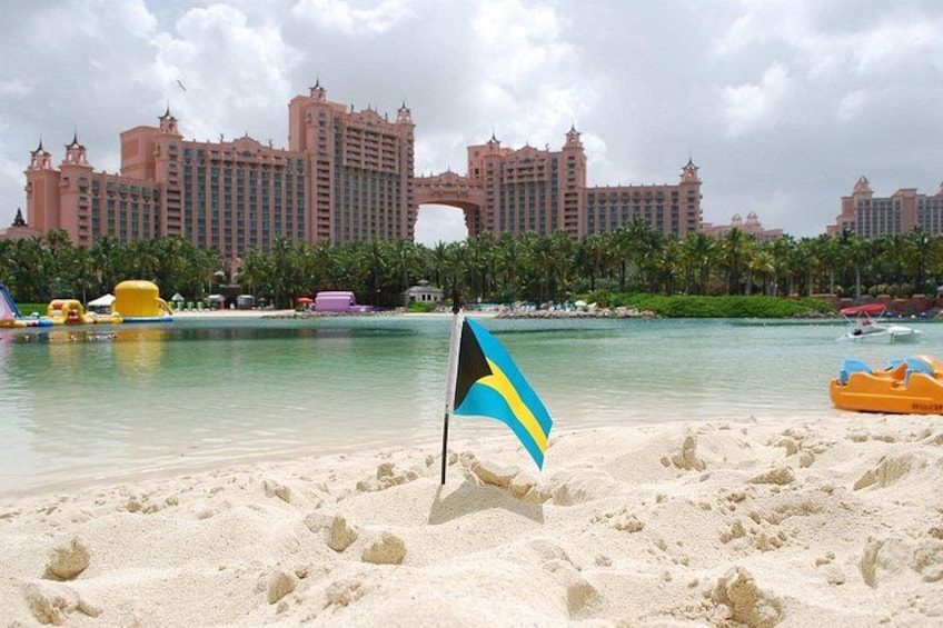 Een strand met een vlag, palmbomen en een groot hotel op de achtergrond. 1
