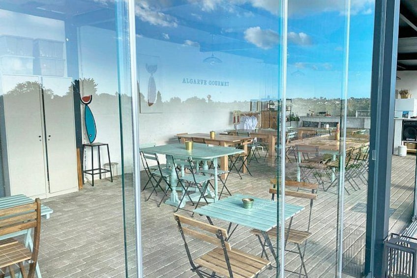 An outdoor dining area with tables and chairs, a wooden deck, and a view of the sky and distant landscape. 2