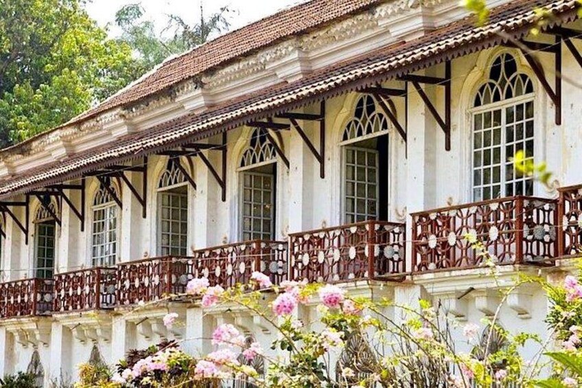 A colonial-style building with arched windows and a balcony with intricate railings. 1