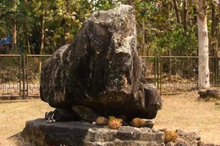 A large rock formation with a rough texture and a smaller rock at its base. 2