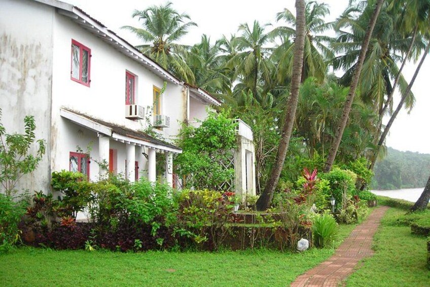 A white building with red accents, surrounded by lush greenery and palm trees. 4