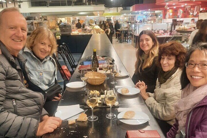 Un groupe de personnes est assis autour d’une longue table, devant de la nourriture et des boissons. 2