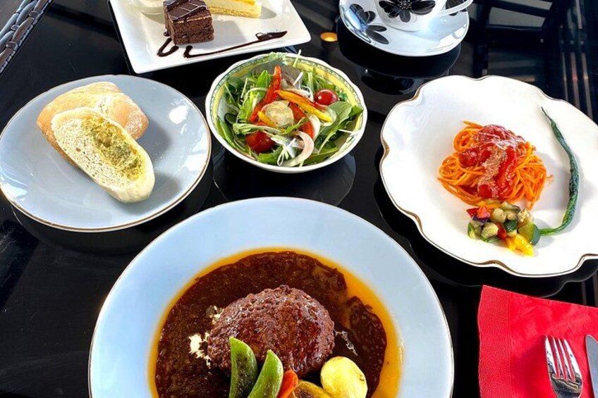 A table with various dishes including a bowl of soup, a plate of spaghetti, a salad, and a piece of cake. 2