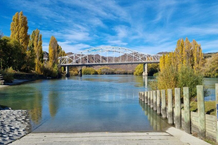 A river with a bridge, wooden fence, and trees. 4