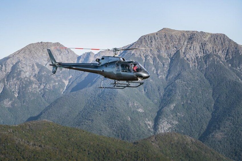Een helikopter vliegt boven een bergachtig landschap. 4