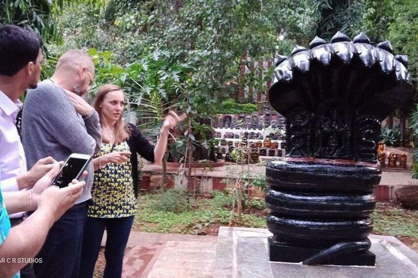 A group of people observing a black, multi-tiered fountain in a garden. 4