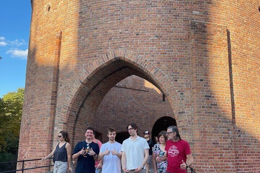 A brick tower with an arched entrance, surrounded by people. 4