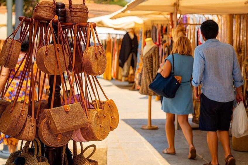 Un puesto de mercado con bolsas tejidas y una pareja mirando. 2