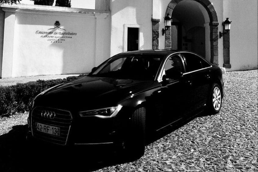A black Audi car parked in front of a building with a sign that reads 'Concerto do Espinho.' 2