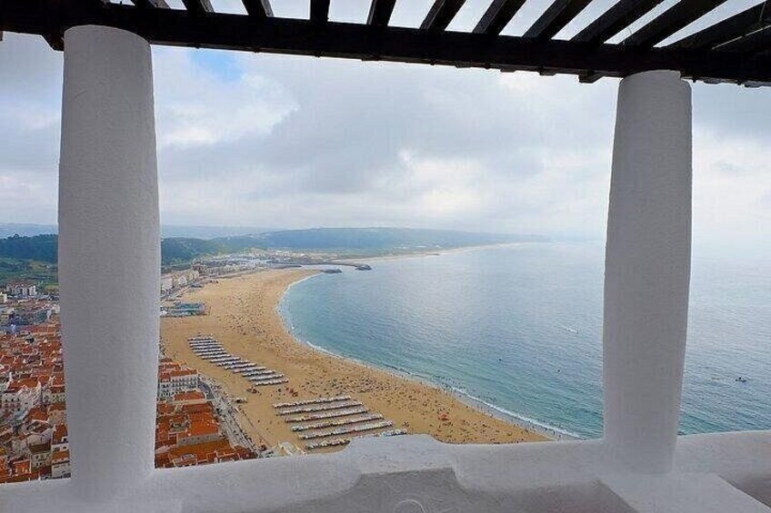 Vista costera con playa, océano y un paisaje urbano al fondo. 4