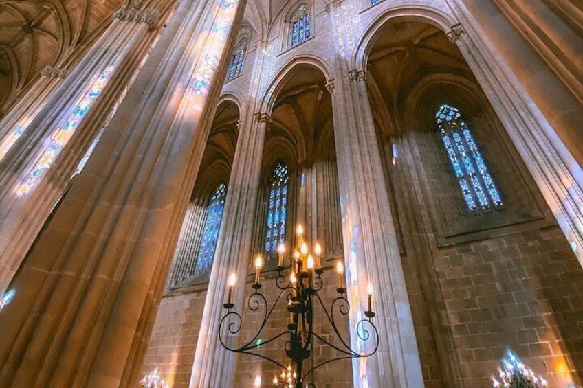 Interior de una catedral con altas columnas, vidrieras y un candelabro. 3