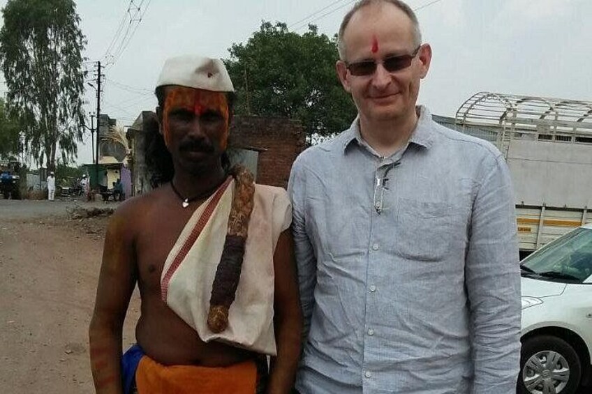 Two men standing outdoors, one in traditional attire and the other in a light blue shirt. 4
