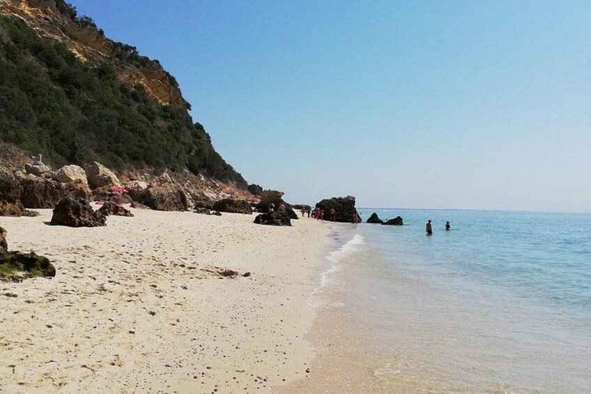 Una spiaggia con acqua cristallina, rocce e un paesaggio collinare. 4